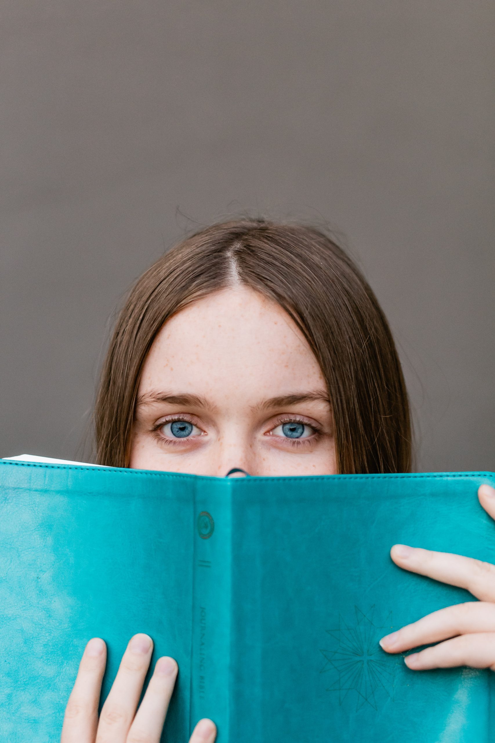 Student peeking over the top of an open book