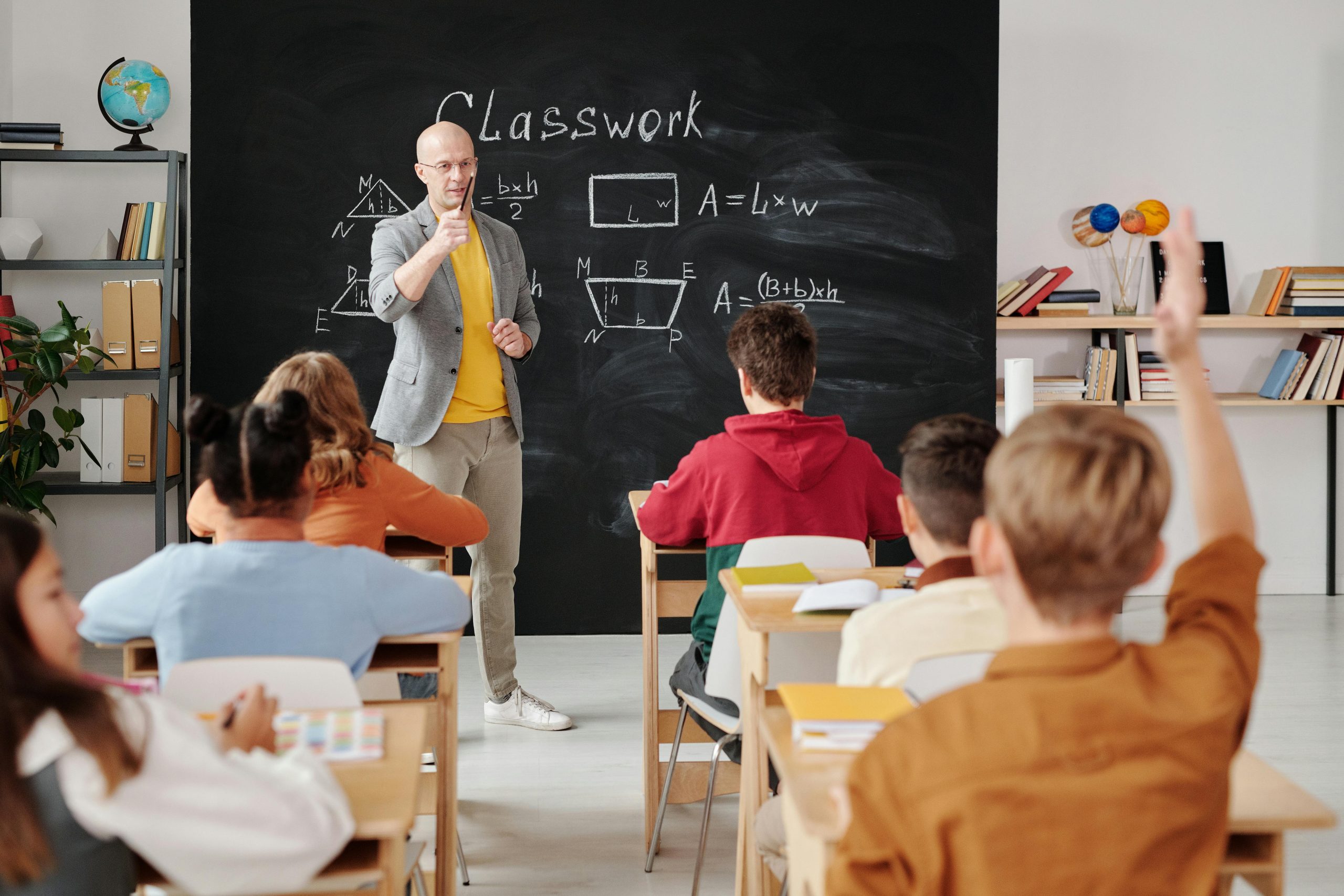 Teacher explaining classwork to students at the blackboard