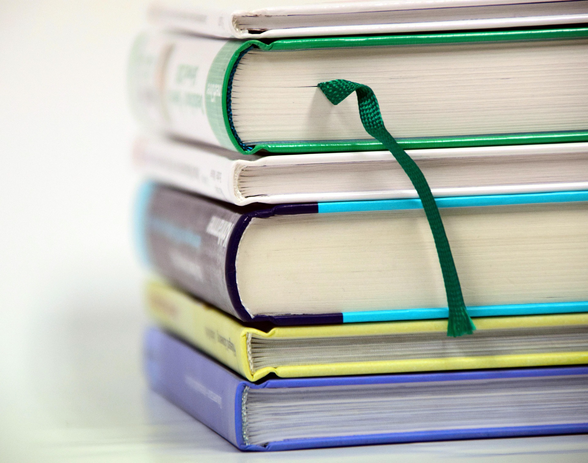 A wicker basket filled with books and pencils sits beside a stack of books topped with a white mug