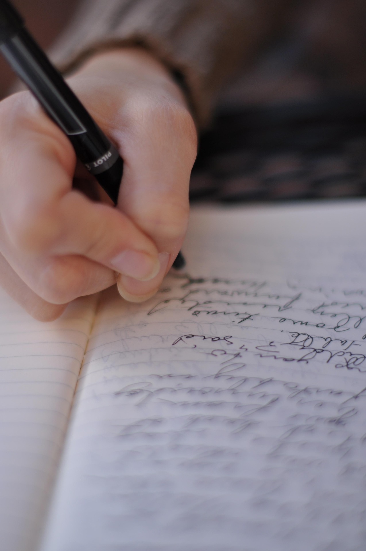 A student writing study notes by hand in a notebook